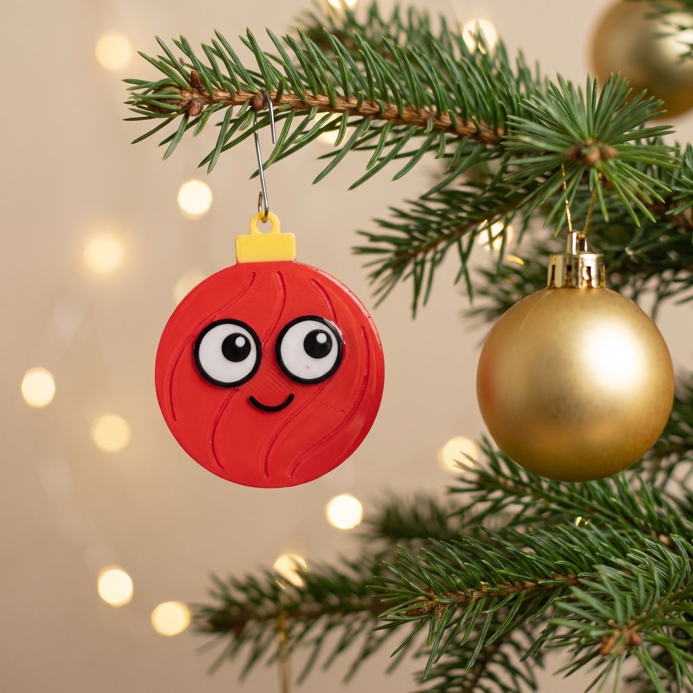 Le magnet Fragilou accroché dans le sapin, à côté d'une boule dorée